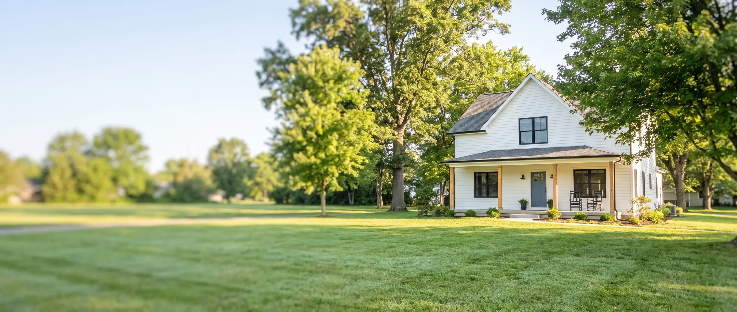 A white two-story home with a front porch and a green lawn in a Southern Indiana neighborhood